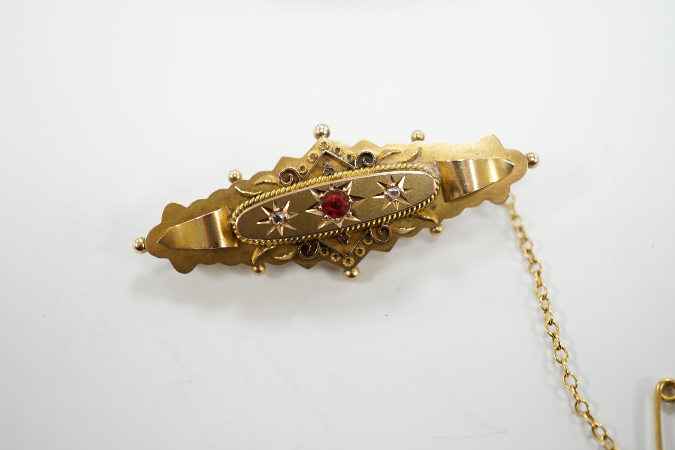 An Edwardian 9ct gold ruby and diamond chip set hinged bangle and a similar yellow metal, ruby and diamond chip set bar brooch, gross weight 12.1 grams.